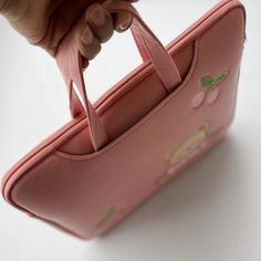 a pink purse being held by someone's hand with the handle extended to it