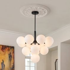 a chandelier hanging from the ceiling in a room with white walls and paintings