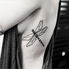 a black and white photo of a woman's chest with a dragonfly tattoo on it