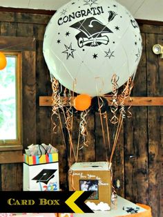 a balloon with congratulations written on it sitting next to a cake and other items in front of a wooden wall