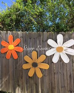 three wooden flowers on a fence with the words star seeds written in white and orange