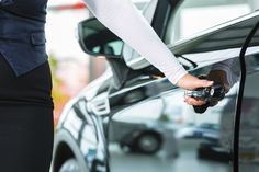 a person holding a cell phone in front of a car