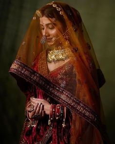 a woman wearing a red and gold bridal veil with her hands on her hips