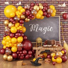 a chalkboard surrounded by balloons, books and other items in front of a brick wall