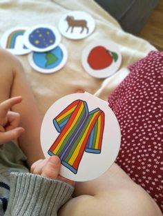 a baby holding up a sticker with an image of a shirt on it