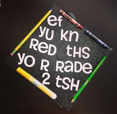 a graduation cap with writing on it and some crayons in front of it