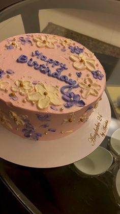 a pink cake with blue and white frosting sitting on top of a glass table