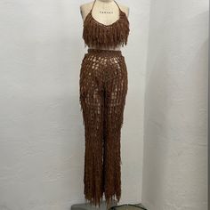 a mannequin is dressed in brown fringes and stands against a white wall