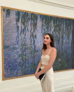 a woman standing in front of a painting