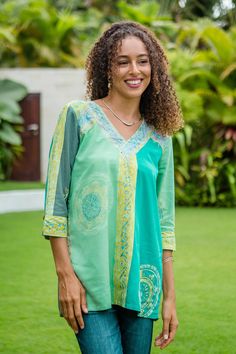 Sea green and soft sage create the soothing color palette on Wayan Arta and Sharon's relaxed-fit blouse. Crafted in Bali, the rayon blouse features a hand-stamped batik motif, a sporty v-neckline, and elegant three-quarter sleeves. With an inverted box pleat on the back and coconut shell button accents, the blouse is charmingly designed. Green Batik Print Top For Summer, Green Tropical Print Cotton Tops, Green Cotton Batik Print Tops, V-neck Block Print Tops For Spring, Batik Motif, Green Batik Print V-neck Dress, Rayon Blouse, Fitted Tunic, Rayon Top