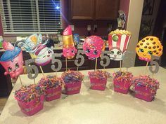 a table topped with cupcakes and cake toppers next to candy buckets