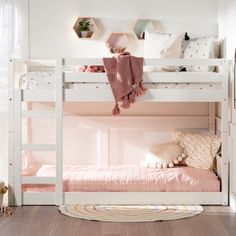 a white bunk bed with pink sheets and pillows