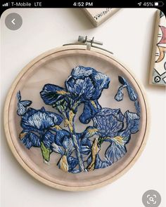 an embroidered blue flower in a wooden hoop next to some other items on a table