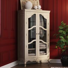 a white china cabinet sitting next to a red wall