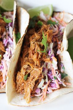 two tacos with shredded meat, cole slaw and cilantro on top