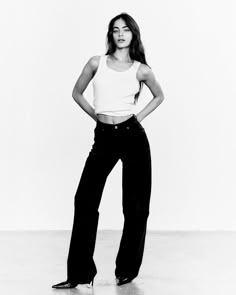 black and white photograph of a woman in high waisted pants with her hands on hips