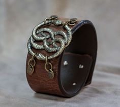 Neverending Story Auryn Bracelet Leather Cuff - Geekify IncGeekify Inc Medieval Style Adjustable Leather Bracelet For Gift, Medieval Style Adjustable Leather Bracelet Gift, Dragon Age Necklace, Adjustable Medieval Leather Bracelet Gift, Ouroboros Bracelet, Edgy Leather Cuff Bracelet, Leather Wristbands Celtic, Adjustable Leather Viking Bracelet, Geek Chic