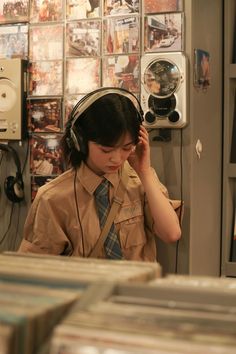 a woman wearing headphones and listening to music in a recording studio with records on the wall