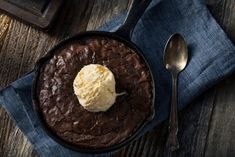 a chocolate cake with ice cream on top is sitting on a blue napkin next to a spoon