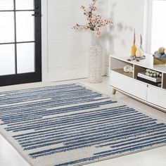 a blue and white rug in a living room next to a vase filled with flowers