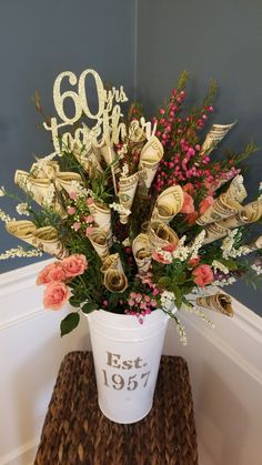 a white bucket filled with lots of flowers on top of a wooden table next to a blue wall