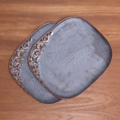 two metal trays sitting on top of a wooden table