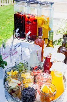 a table topped with jars filled with different types of drinks and fruit on top of it