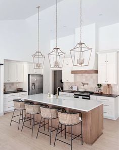 a large kitchen with white cabinets and an island in the middle is surrounded by wicker bar stools