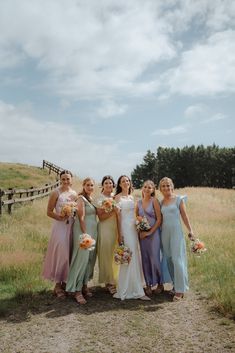 a group of women standing next to each other in front of a fence and grass field