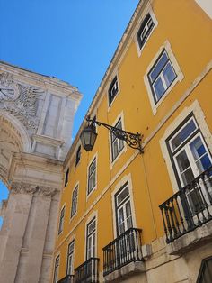 a tall yellow building with a clock on it's face and balcony railings