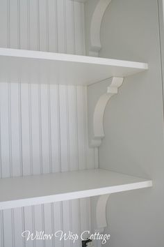 two white shelves in the corner of a room