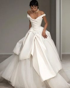 a woman in a white wedding dress walking down the runway with her hand on her hip