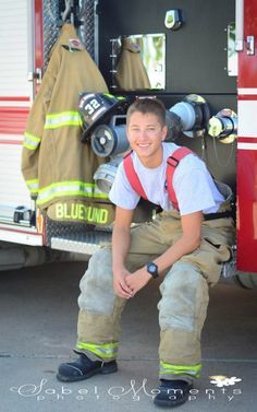 a young man kneeling in front of a fire truck