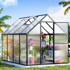 a small greenhouse with lots of flowers in the yard and palm trees behind it,