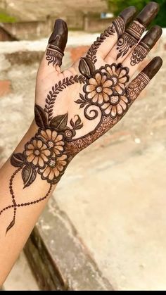 a woman's hand with henna tattoos on it and flowers in the middle