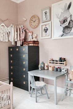 a baby's room with pink walls and pictures on the wall, including clothes