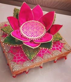 a pink flower sitting on top of a wooden box covered in jewels and pearls,