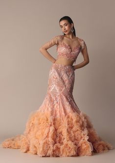 Epitomizing elegant beauty our stunning peach lehenga set adds a touch of femininity to your glamorous look. Elevated with floral detailing and sleek 3D frills the fish cut silhouette accentuates your curves. Complemented with an embroidered trail dupatta that enhances the ensemble with its ethereal beauty. Perfect for Elegant Fitted Orange Lehenga, Fitted Peach Dress For Reception, Glamorous Fitted Lehenga With Ruffles, Fitted Peach Lehenga For Party, Fitted Peach Sets For Reception, Frill Lehenga, Fish Cut Lehenga, Fish Cut Gown, Orange Pictures