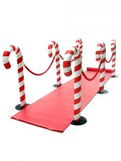 a man standing next to red and white candy canes on top of a red carpet