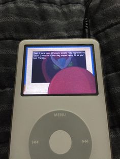 an ipod is sitting on top of a bed with the screen turned off and music player hooked up to it