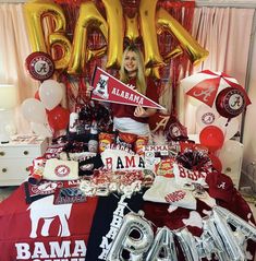 a woman sitting in front of a bed with balloons and decorations