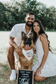 a man and woman pose for a photo with their dog in front of a sign