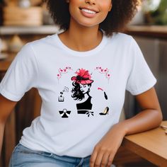 Elevate your style with this chic and sophisticated women's tee shirt that exudes elegance and glamour. At the center of the design is a striking silhouette face of a sophisticated woman, exuding confidence and grace. Adorned with a cute fascinator hat, she is the epitome of timeless beauty and sophistication. Flanking the face on either side, images of a lipstick and a perfume bottle add to the allure of the design. The lipstick, with a small pink lipstick smudge effect, symbolizes femininity a Silhouette Face, Classy Accessories, Lipstick Smudge, Heels High Classy, Fascinator Hat, Pink Lipstick, Statement Tees, Woman Silhouette, Look Chic