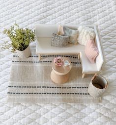 a white couch sitting on top of a bed next to a wooden table and potted plants