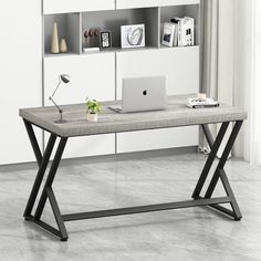 a computer desk with a laptop on it in front of a bookcase and bookshelf