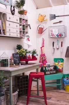 a room filled with lots of potted plants next to a wooden table and chairs