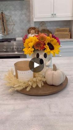 a teddy bear sitting on top of a counter next to a vase filled with sunflowers