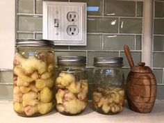 three jars filled with food sitting on top of a counter next to a light switch