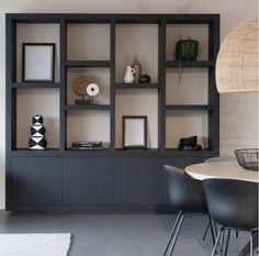 a living room filled with furniture next to a wall mounted bookcase and a round table