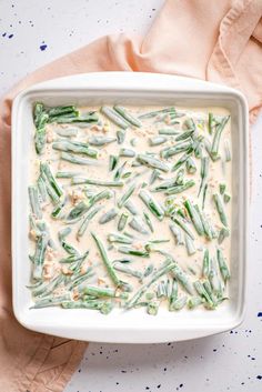 a white dish filled with green beans and cream